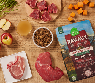 Open Farm Rawmix front range recipe package with raw meat, apples, and other ingredients on a wooden surface